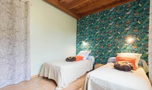 A room with two beds, a patterned curtain, and a wall with a leaf and animal print. - La Ferme de Thière - Fontenilles (Fontenilles)