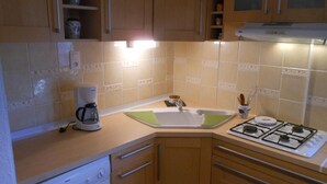 Une cuisine compacte équipée d’un lave-linge, d’une machine à café et d’une cuisinière.