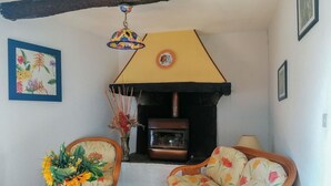 Un salon chaleureux avec une cheminée, des meubles en osier et des décorations florales.