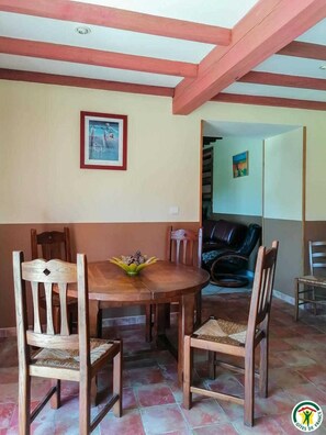 Cozy dining area with a wooden table and four chairs, a black leather chair, and a framed picture on the wall.