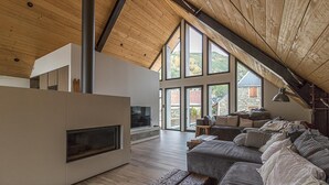 A modern loft with a large fireplace, wooden beams, and a cozy seating area with a view of the countryside. - La Grange de Mayrègne - MAYREGNE (MAYREGNE)