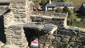 A stone structure with a small opening, a bag of fertilizer, and houses in the background. - La Grange de Mayrègne - MAYREGNE (MAYREGNE)