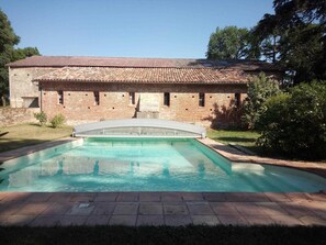 Ein Schwimmbecken mit einem Backsteinhaus im Hintergrund.