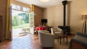 A living room with a fireplace, a TV, and a dining area with a red tablecloth.
