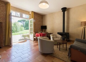 Un salon avec une cheminée, un téléviseur et un coin repas agrémenté d’une nappe rouge.