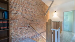 Un escalier avec un mur en briques, une rampe en bois et une bibliothèque remplie de livres.