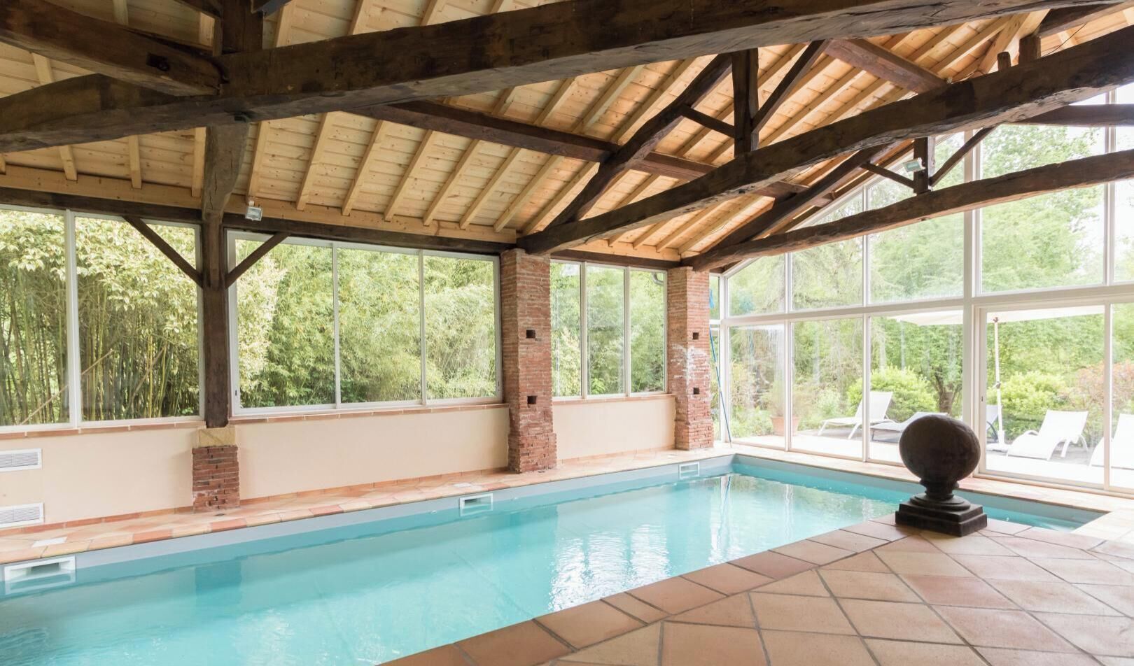 An indoor swimming pool with a wooden ceiling and large windows.