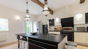 Een moderne keuken met een centraal eiland, hanglampen en uitzicht op buiten.