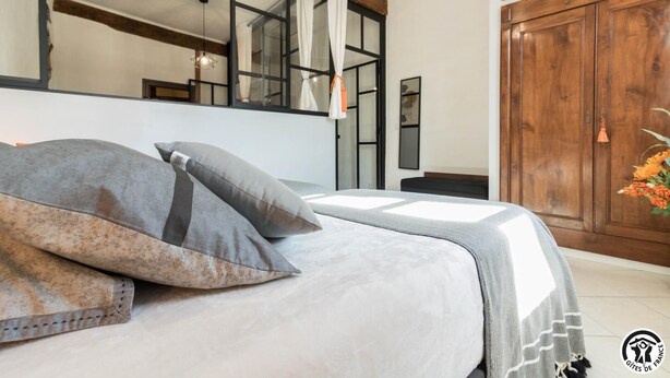 A bedroom with a bed, pillows, a wooden wardrobe, and a mirror. - Escapade Lauragaise - Saint-Félix-Lauragais (Saint-Félix-Lauragais)