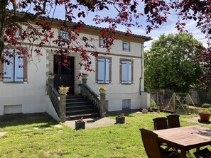 A two-story house with a stone staircase leading to the entrance, a front porch with potted plants, and a small outdoor seating area with a table and chairs. - Brouillous - Villaudric (Villaudric)