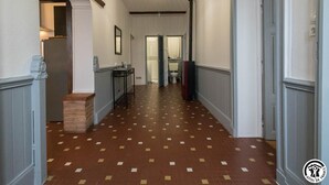 En hall med bruna och beige kakelplattor i ett mönster, vita väggar och en taklampa.