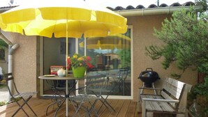 An outdoor patio with a yellow umbrella, a table with chairs, a potted plant, and a barbecue grill. - Green Valley - Villaudric (Villaudric)
