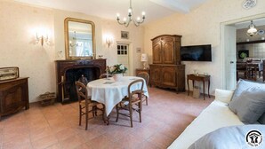 Un comedor con una mesa redonda, sillas, chimenea y un espejo en la pared.