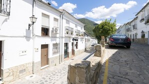 A narrow cobblestone street lined with white buildings, a parked car, and a mountain in the background. - Casa Paula in Benamahoma (Grazalema)