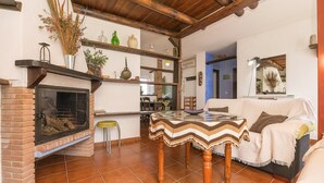 A cozy living room with a fireplace, a dining area, and a sofa. - Casa Paula in Benamahoma (Grazalema)