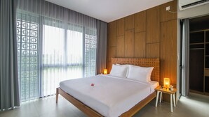 Een moderne hotelkamer met een groot bed, houten paneelwanden, een balkon met gordijnen en een kledingkast.