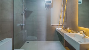 Een moderne badkamer met een glazen douchecabine, een wit wastafeltje en een spiegel.
