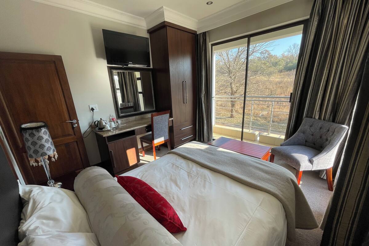 Ein Hotelzimmer mit Bett, Schreibtisch mit Fernseher, Stuhl und Balkon mit Aussicht.