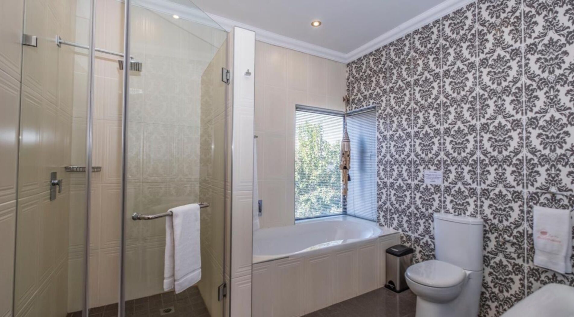 A bathroom with a glass shower enclosure, a bathtub, and a toilet.