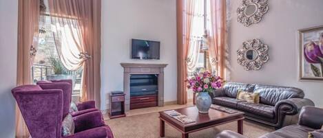 Ein Wohnzimmer mit Kamin, Fernseher, Sofa und Couchtisch.