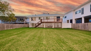 Um imóvel residencial com quintal cercado, deck de madeira e área de varanda coberta.