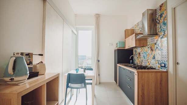 A compact kitchen with a dining area, a view through a window, and a kitchenette with a stove and cabinets.