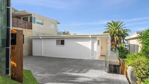A modern building with a paved driveway, a small window, and a glass door.