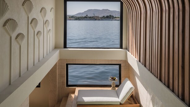 Un cuarto de spa con vista a una masa de agua, una bañera y una pequeña mesa con un frutero.