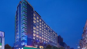 Un hotel de gran altura con varios pisos, ventanas iluminadas y un diseño arquitectónico moderno.