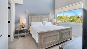A bedroom with a bed, bedside tables, and a window with a view of greenery.