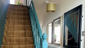 Eine Treppe mit blauer Geländer, einem gemusterten Teppich und einer Deckenleuchte.