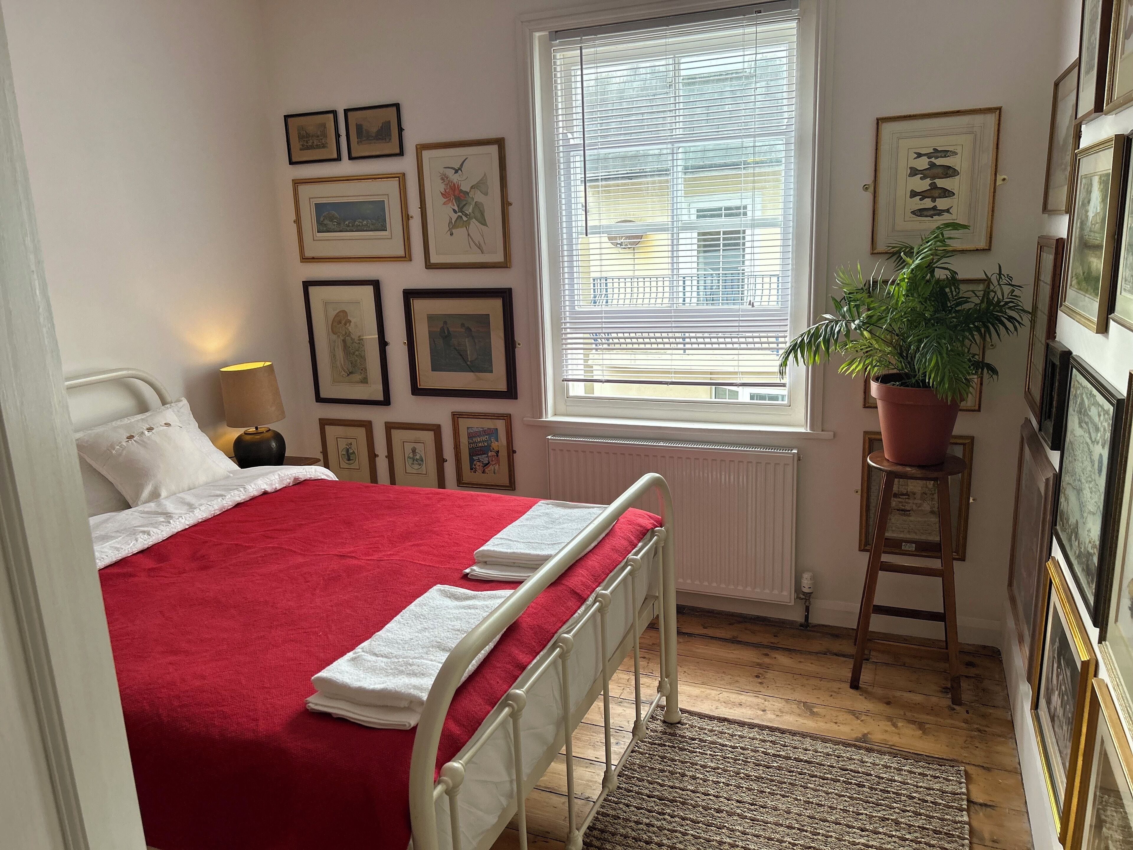 A bedroom with a bed, a window, and framed pictures on the wall.