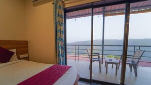 A hotel room with a large bed, a balcony with a view of the sea, and a table and chairs outside. - Trattino Resorts (Wai)