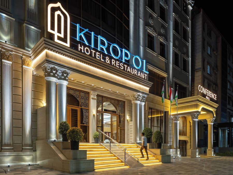 A hotel entrance with a grand staircase, columns, and a sign for 'Kiropol Hotel & Restaurant'.