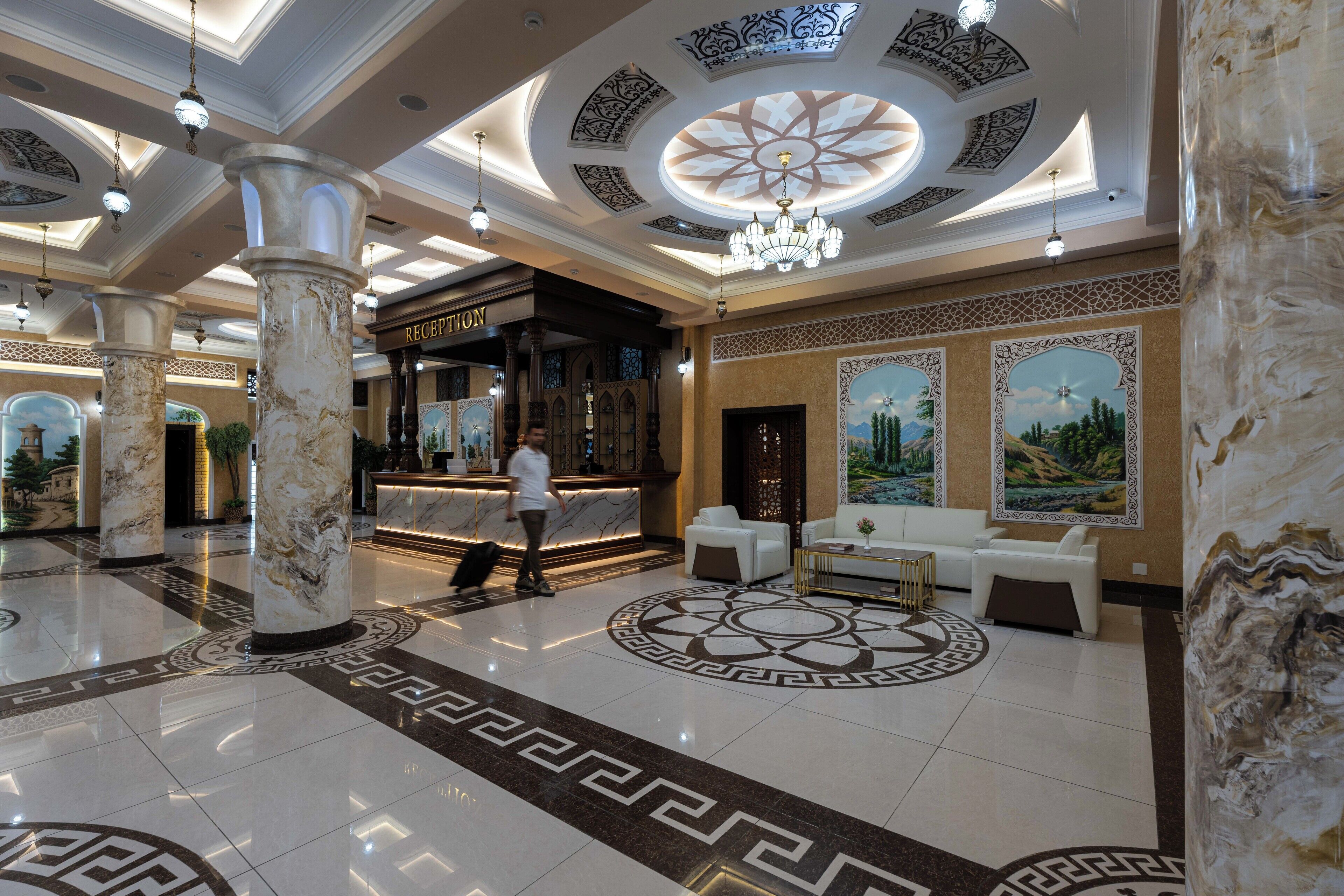 A lobby with marble columns, a reception desk, and a chandelier.