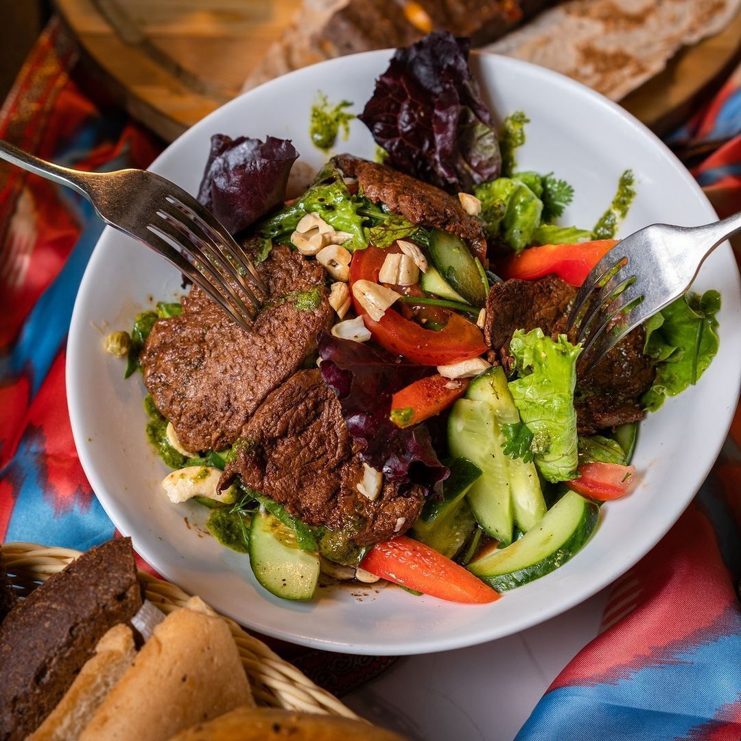 Une assiette de nourriture comprenant de la viande, des légumes et des noix.
