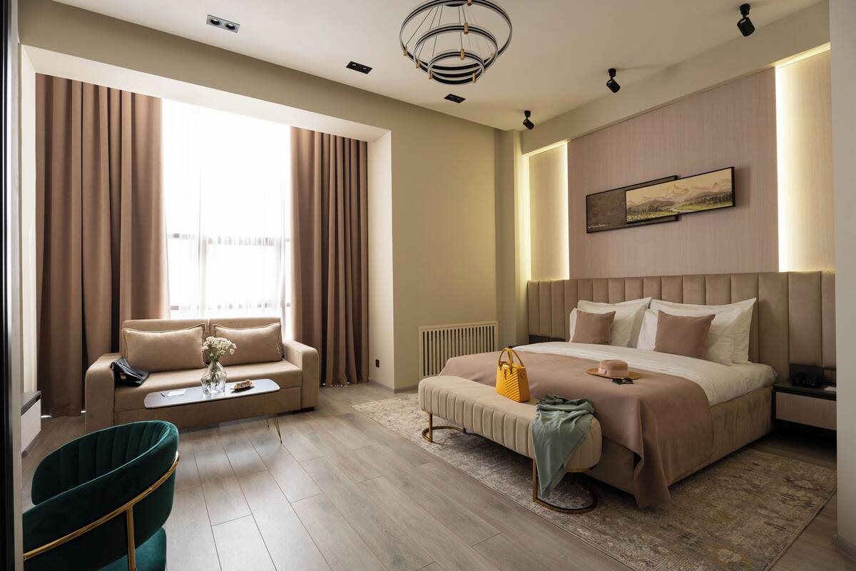 Ein modernes Hotelzimmer mit einem großen Bett, einer Couch, einem Couchtisch und Blick auf die Stadt.
