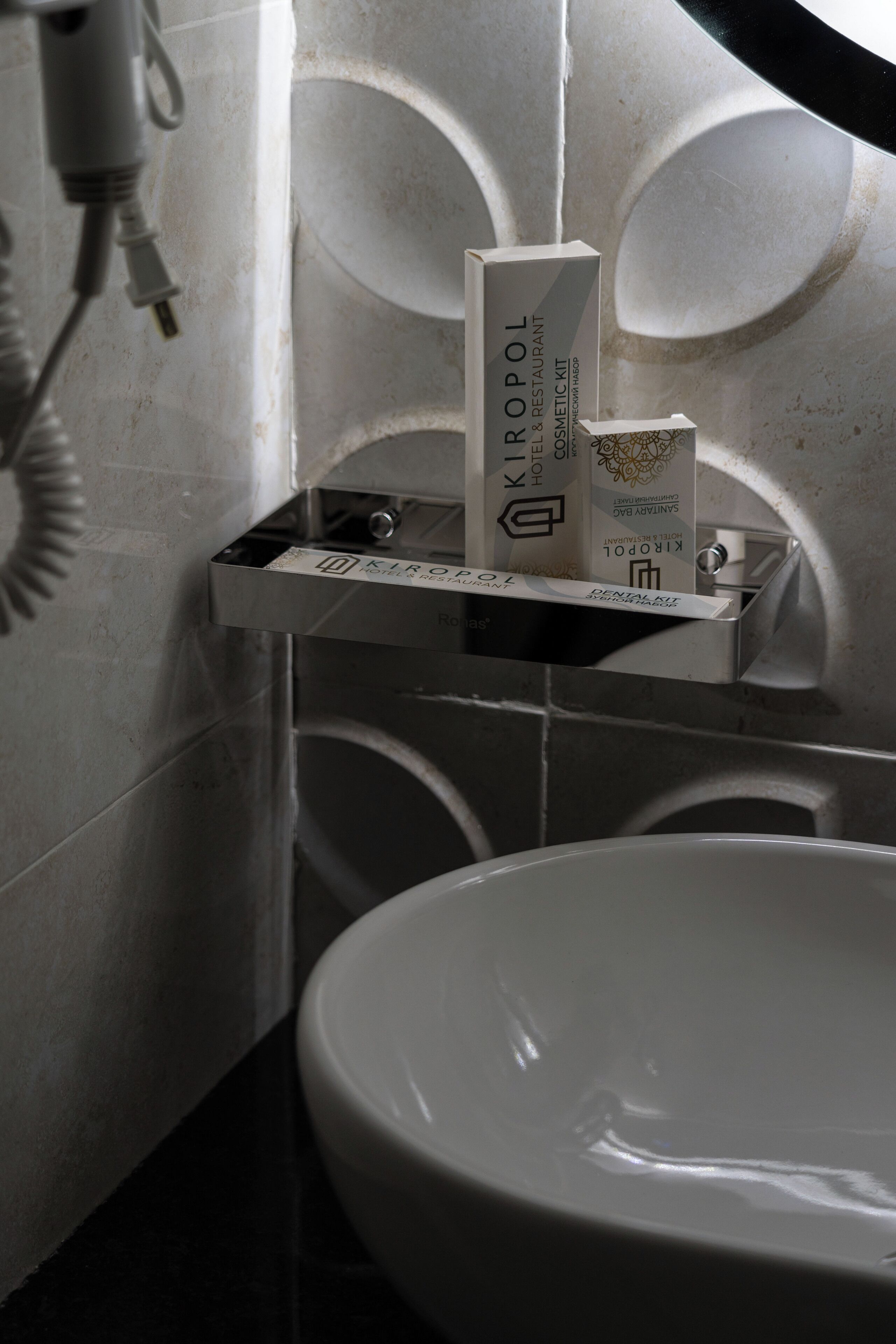 A bathroom with a white sink, a towel rack, and a box labeled "KIROPOL HOTEL & RESTAURANT".
