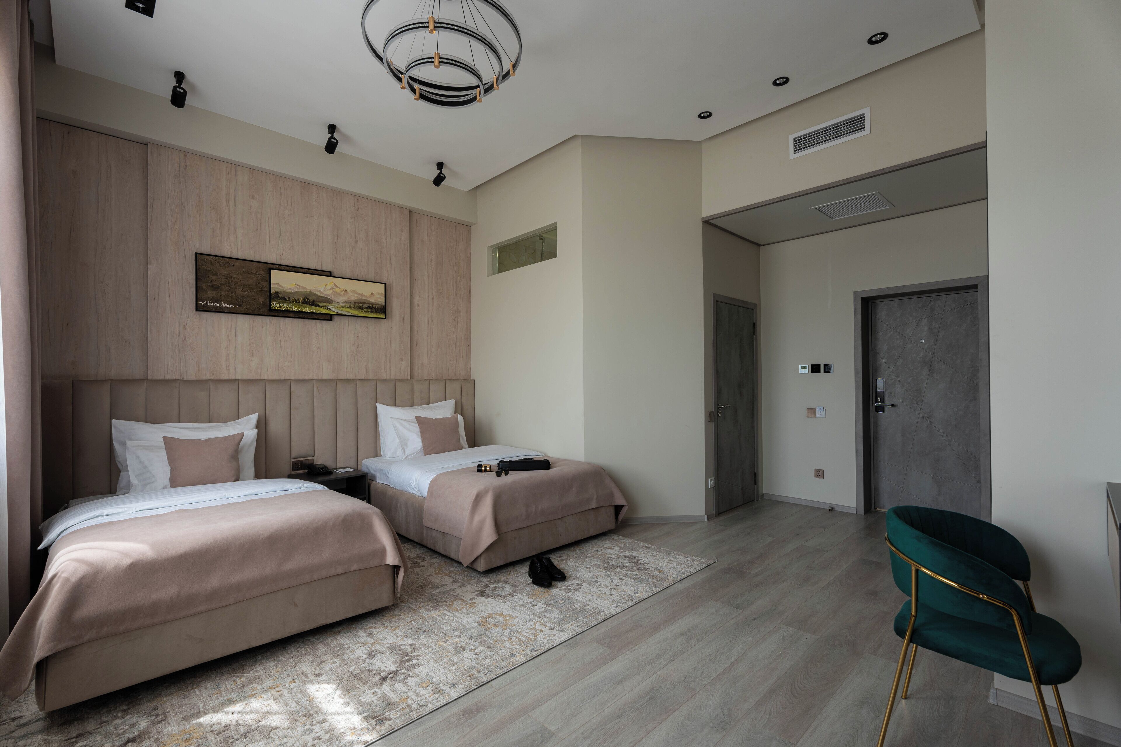 A modern hotel room with two beds, a large artwork on the wall, and a unique green chair.