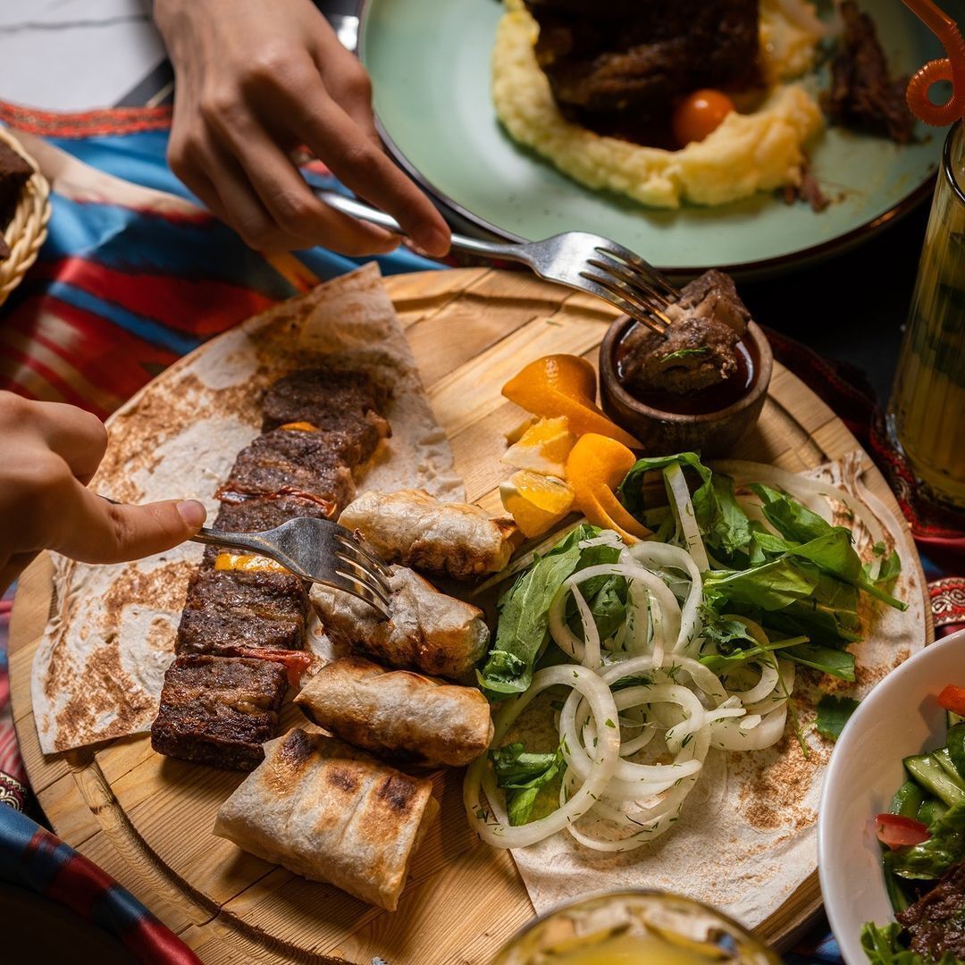En måltid bestående av grillat kött, tunnbröd och sallad, serverad på en träbricka.