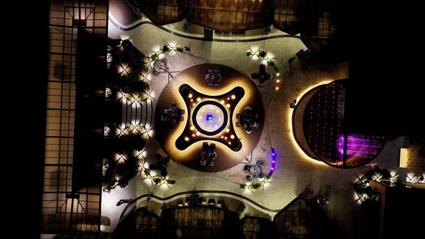 Un vaste atrium doté d’un luminaire circulaire central, entouré d’espaces de détente et surmonté d’une grande verrière circulaire.