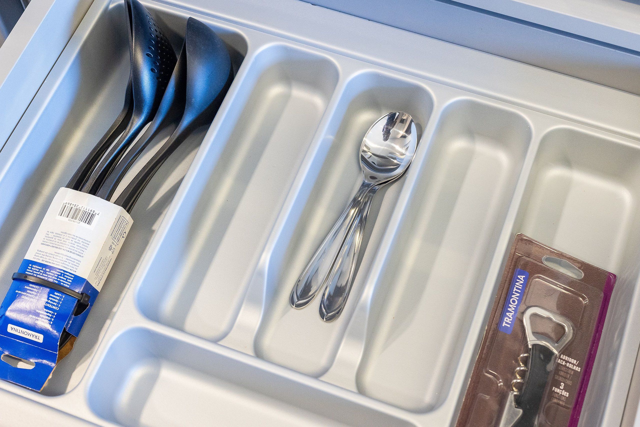 A compartmentalized drawer with utensils, a box, and a package.