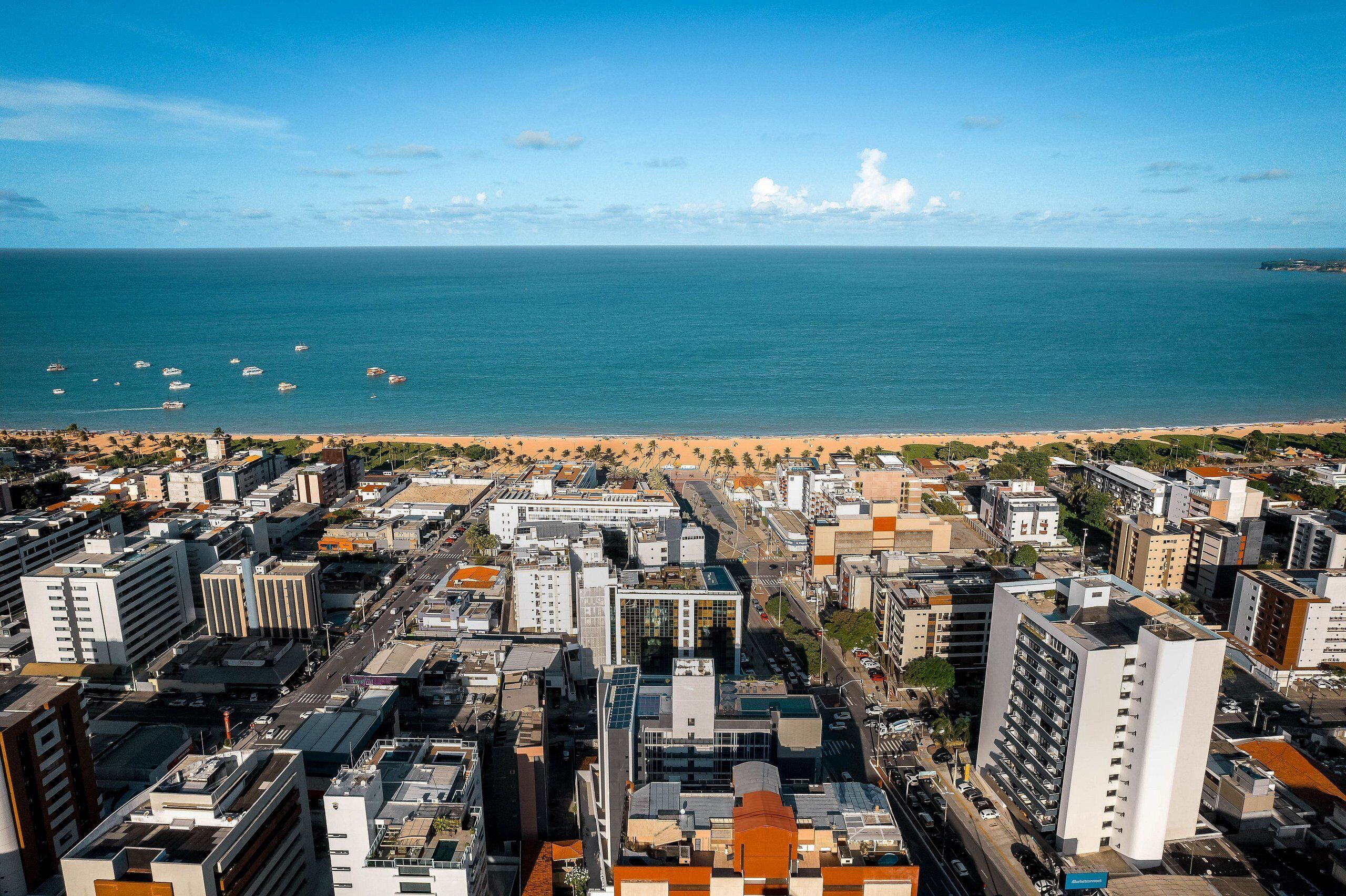 Eine Küstenstadt mit Strand, Hochhäusern und wolkenlosem Himmel.