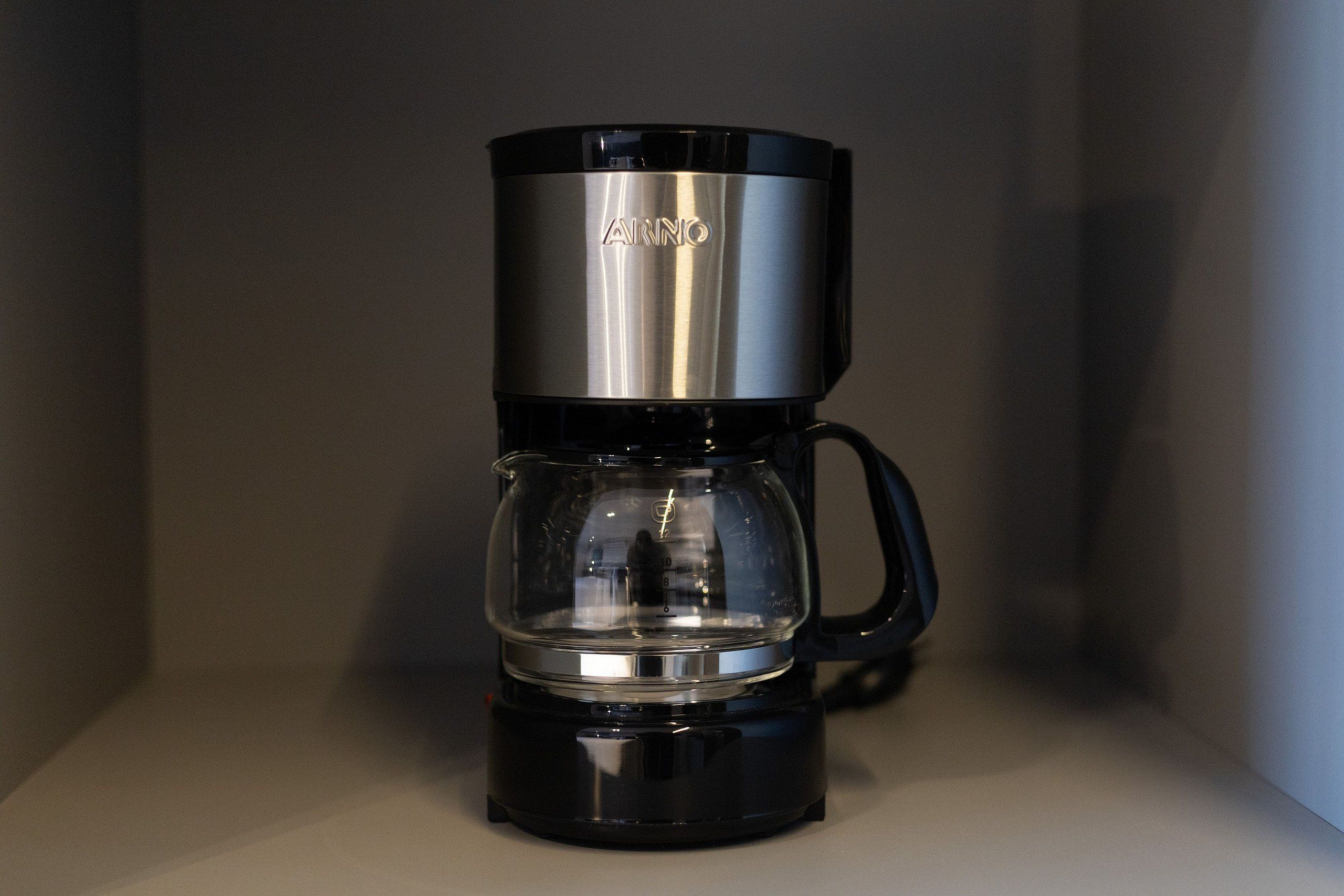 A black and silver coffee maker with a clear glass carafe and a handle on the side.