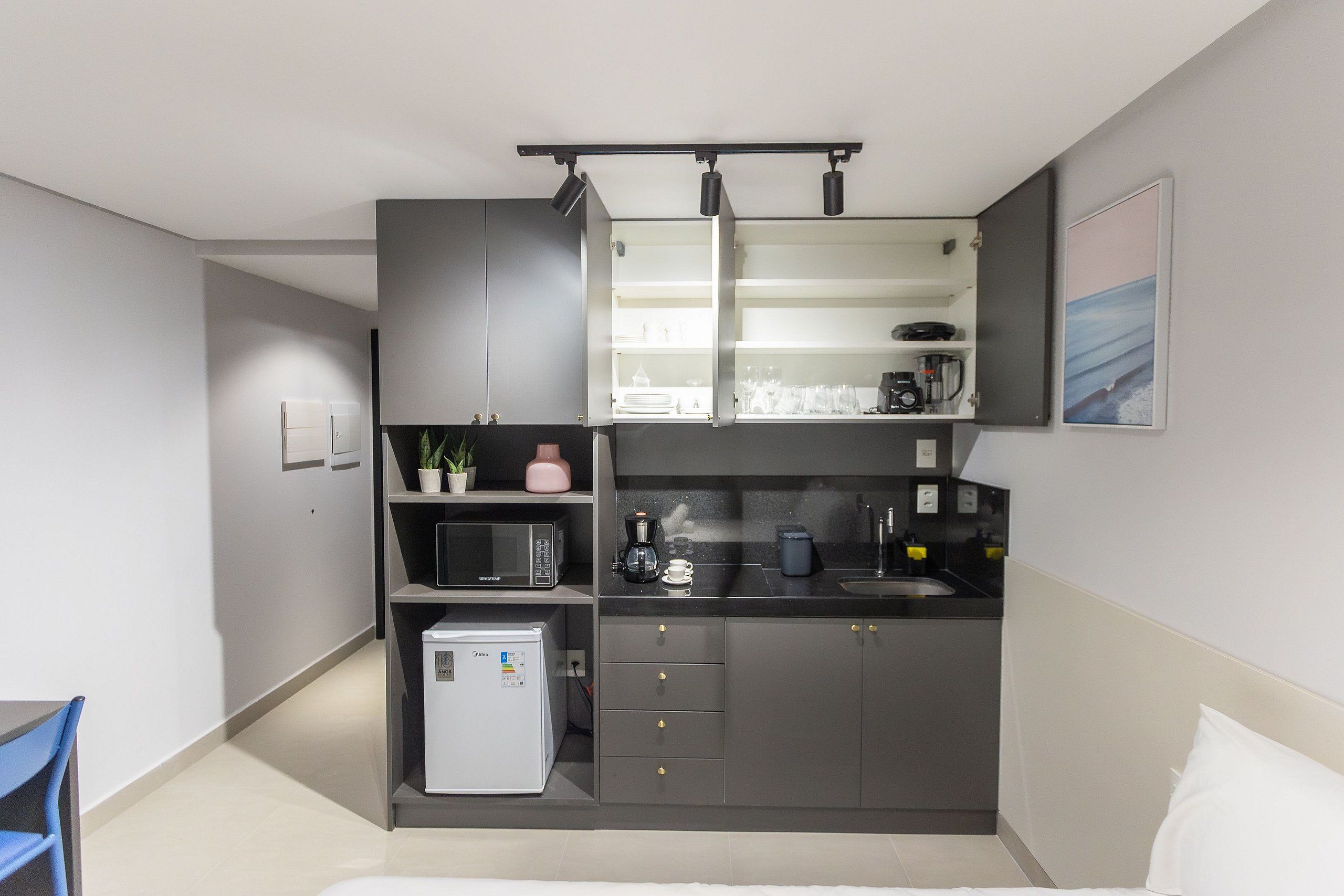 Una cocina compacta equipada con microondas, cafetera y un refrigerador pequeño.