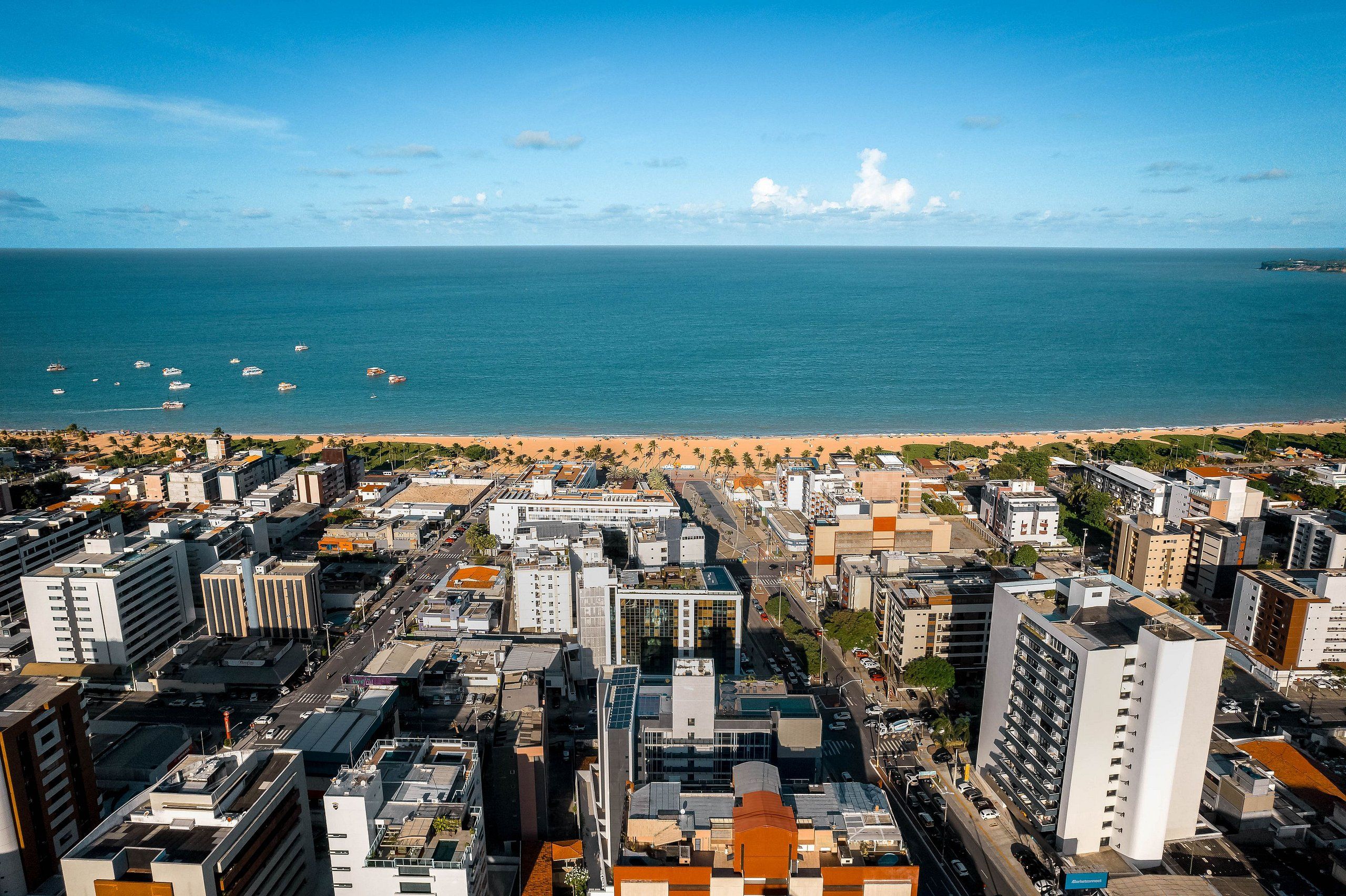 Un paisaje urbano costero con una playa, rascacielos y cielo despejado.