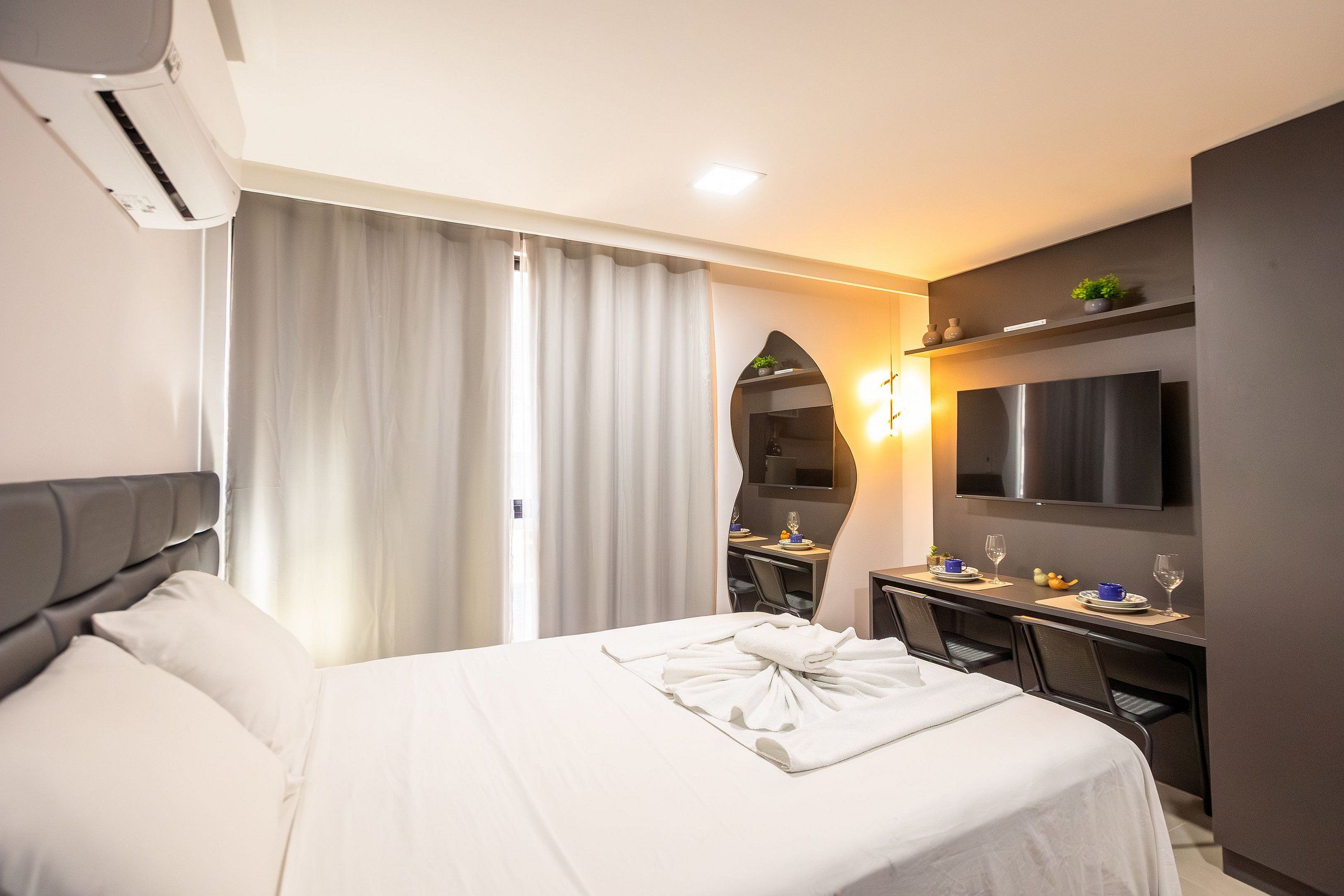 Una habitación de hotel con una cama, un escritorio, un televisor y un espejo.