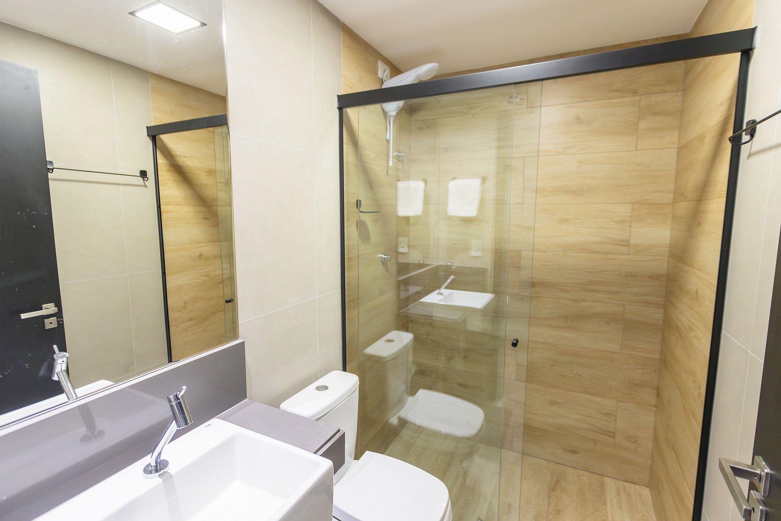 A modern bathroom with a glass-enclosed shower, a sink, and a toilet.