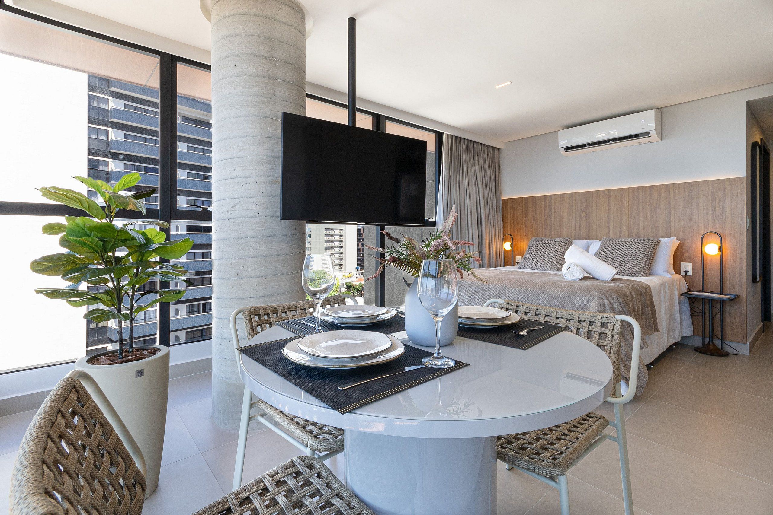 Une chambre d’hôtel moderne dotée d’un coin repas, d’un lit et d’une grande fenêtre offrant une vue sur la ville.