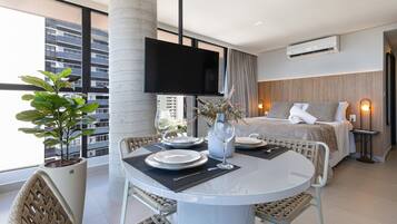 Une chambre d’hôtel moderne dotée d’un coin repas, d’un lit et d’une grande fenêtre offrant une vue sur la ville.